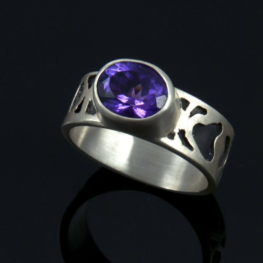 Silver ring with purple gem stone, photograph.