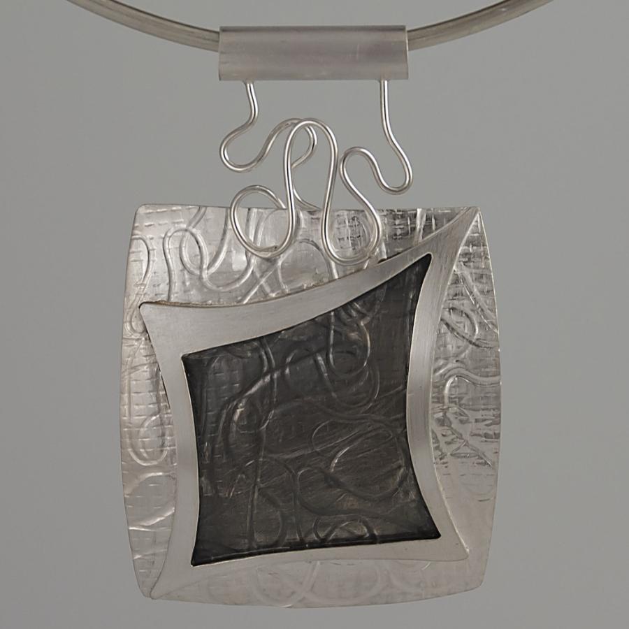 Silver necklace with square patterned pendant.