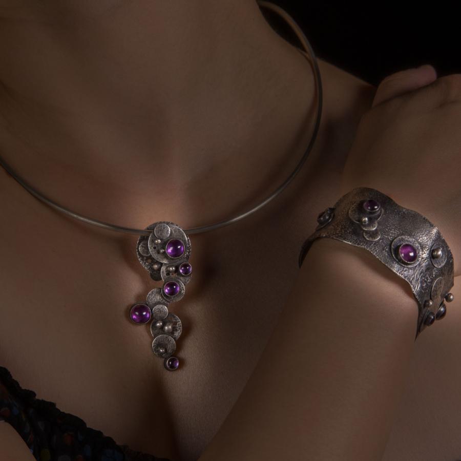 Woman wearing silver necklace and bracelet with pink stones.
