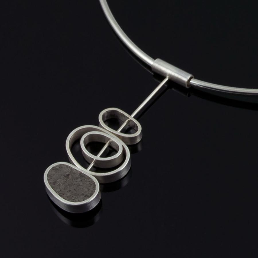 Silver pendant against a black background.