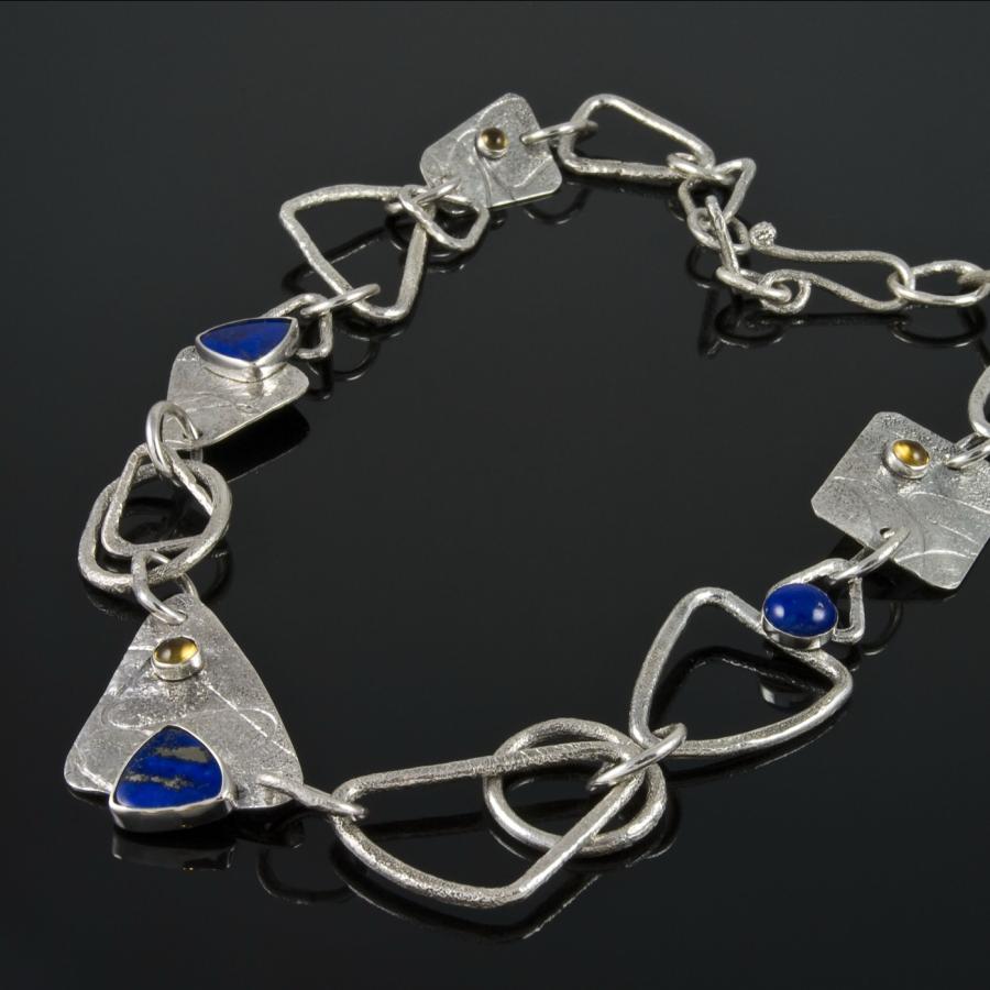 Silver necklace with blue and yellow stones, studio shot.