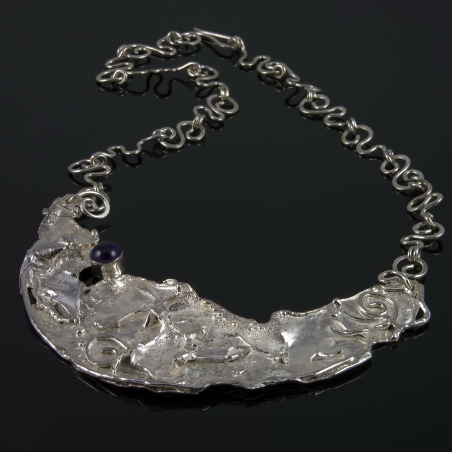 Silver necklace with amethyst on black background.