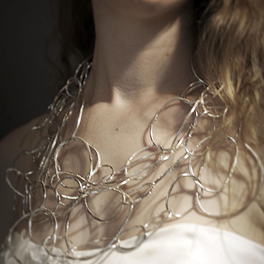 Woman smiling wearing silver necklace and wedding dress.