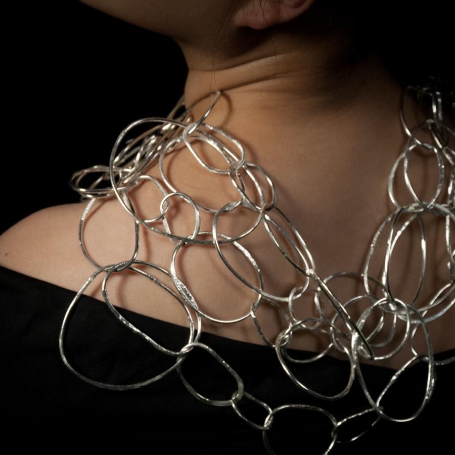 Woman wearing a silver chain-link necklace, photograph.