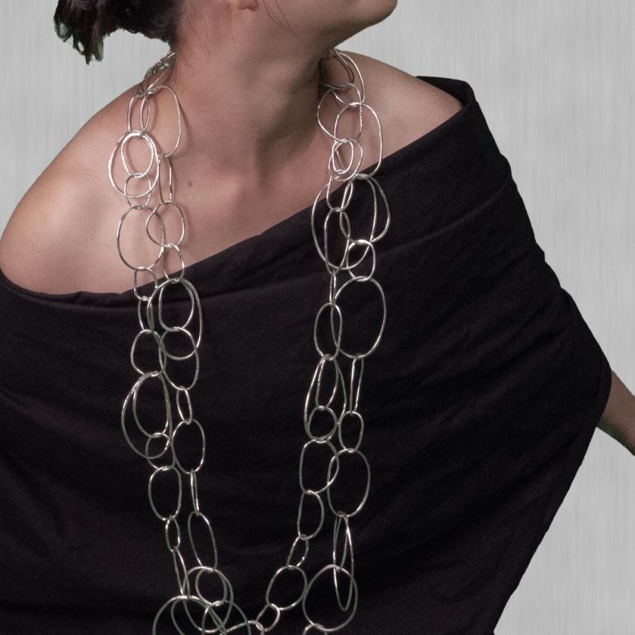 Woman in black wearing silver looped necklace.
