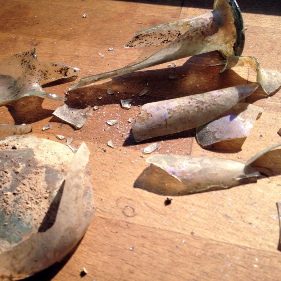 Broken vase with shards scattered on a wooden surface.