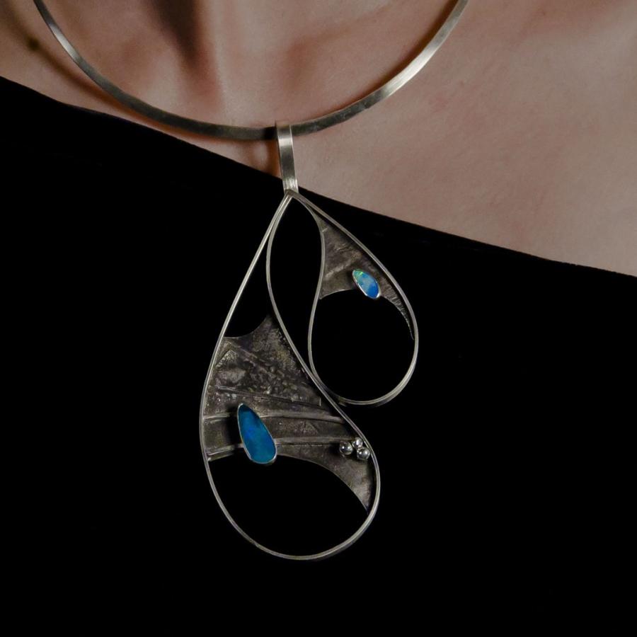 Silver necklace with asymmetrical teardrop shapes and opal on a female model.