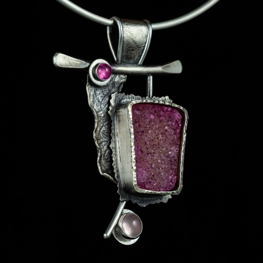 Silver necklace with pink stones, on black.