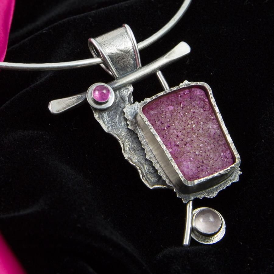Silver necklace with a pink stone pendant.