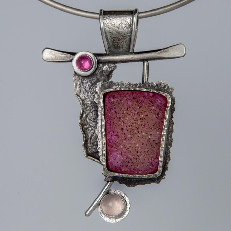 Silver necklace with rough pink stone pendant.