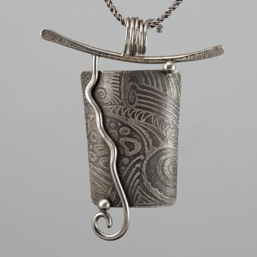 Silver necklace with textured pendant.