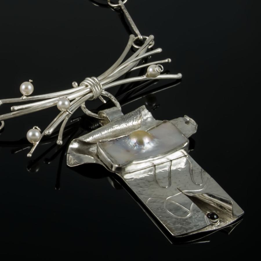 Silver pendant necklace on black background.