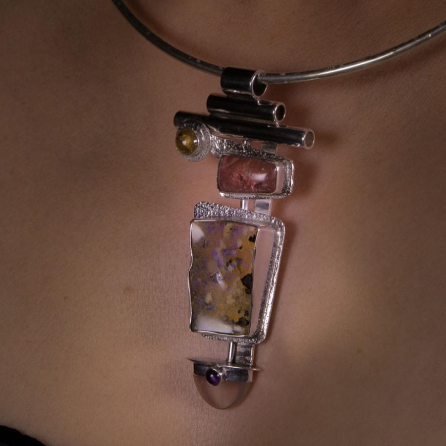 Silver choker necklace with colorful pendant on person.