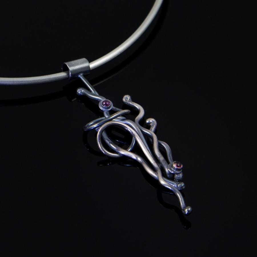 Silver pendant necklace on a black background.