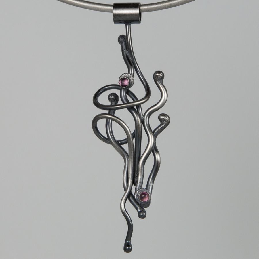 Silver necklace with abstract swirl pendant and pink gemstones.