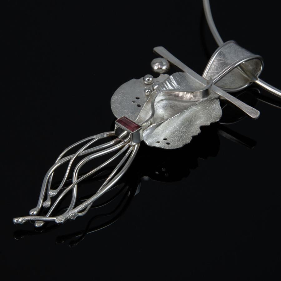 Silver pendant necklace on a black background.