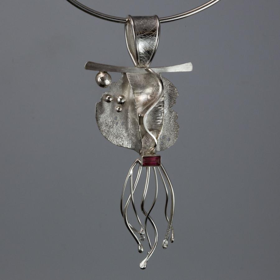 Silver pendant necklace on gray background.