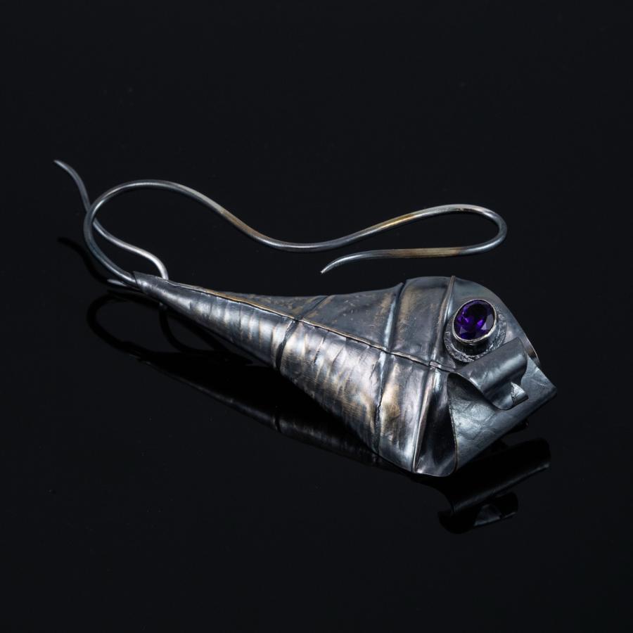 Close-up of a silver brooch with a purple gem.