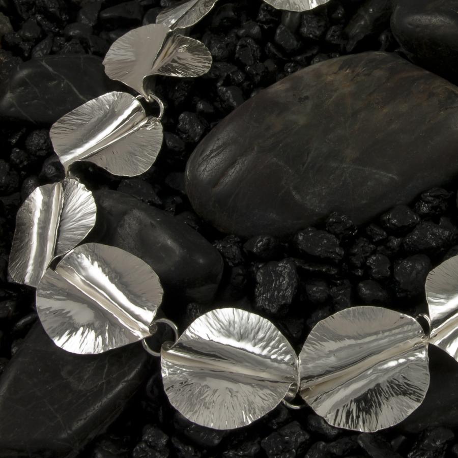 Silver bracelet on black pebbles.
