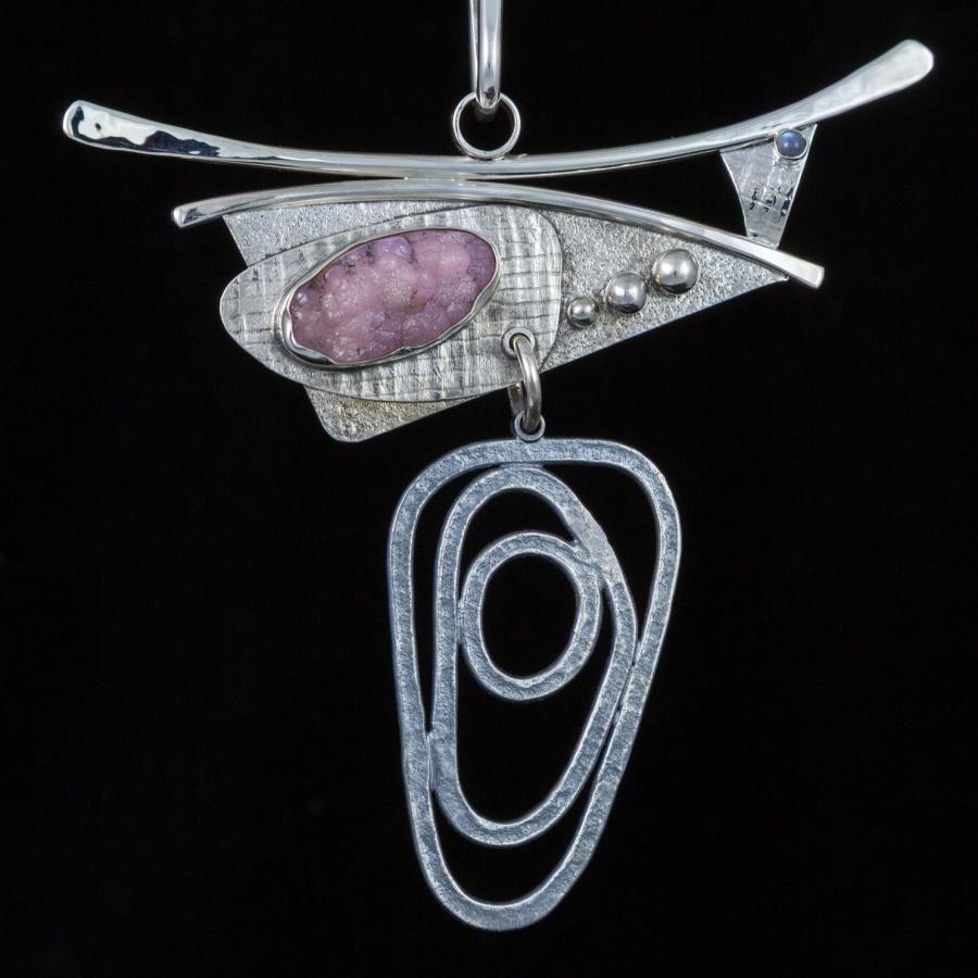 Necklace with abstract silver pendant and pink stone.