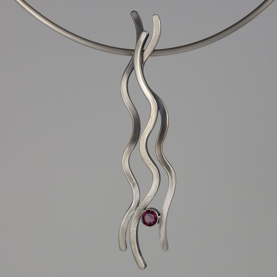 Silver necklace with wavy pendant and pink stone.