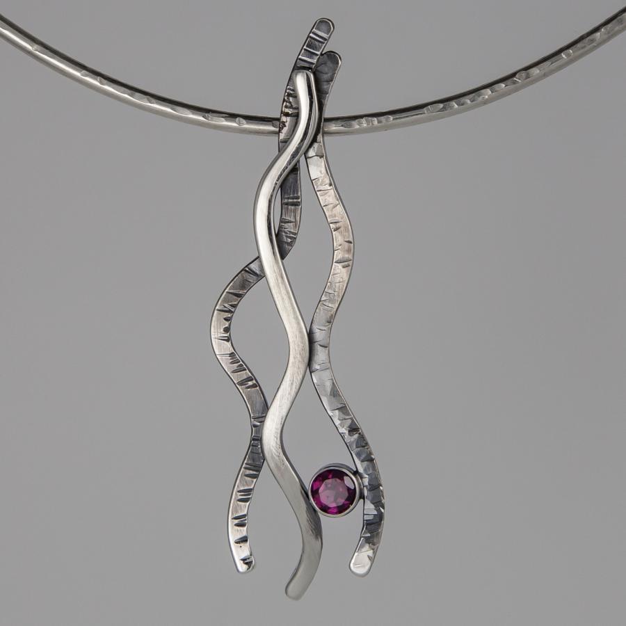 Silver necklace with a wavy pendant and pink stone.