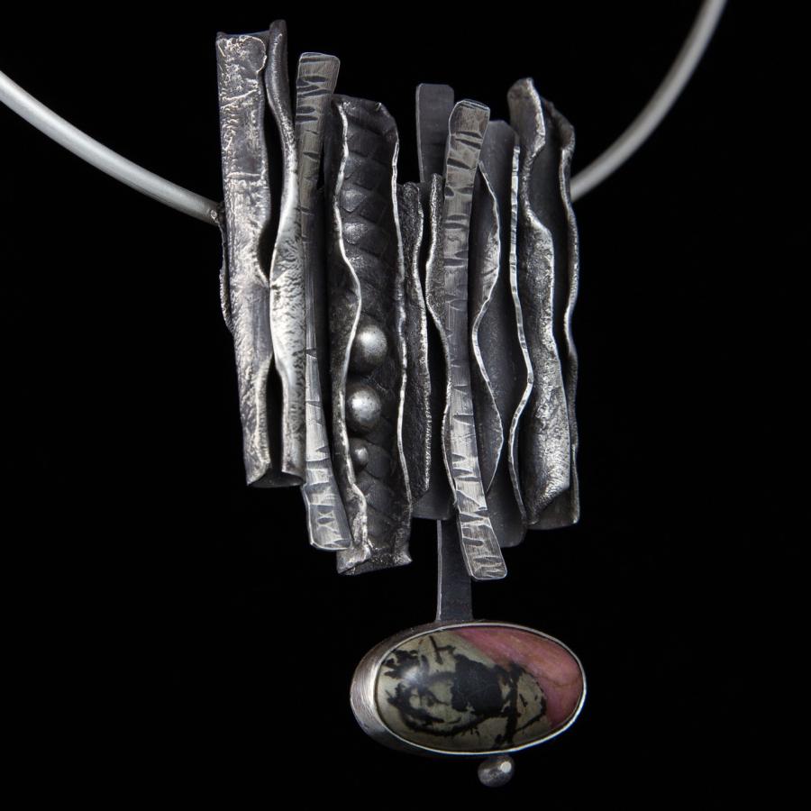 Silver pendant necklace on a black background.