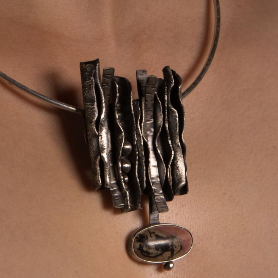 Necklace with abstract silver pendant on a person.