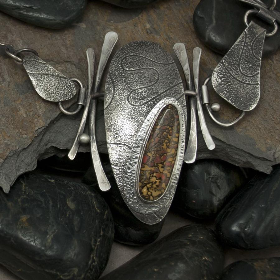 Handcrafted silver jewelry on stone, photograph.