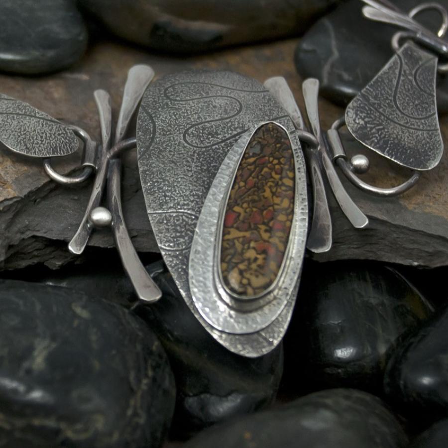 Handcrafted silver jewelry on stone, photograph.