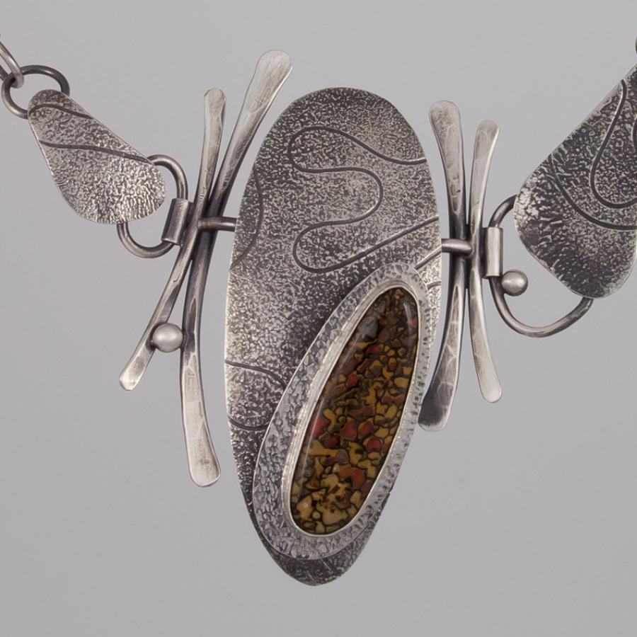 Silver necklace with textured pendant.