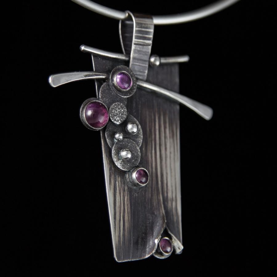 Silver pendant with purple stones on a chain.