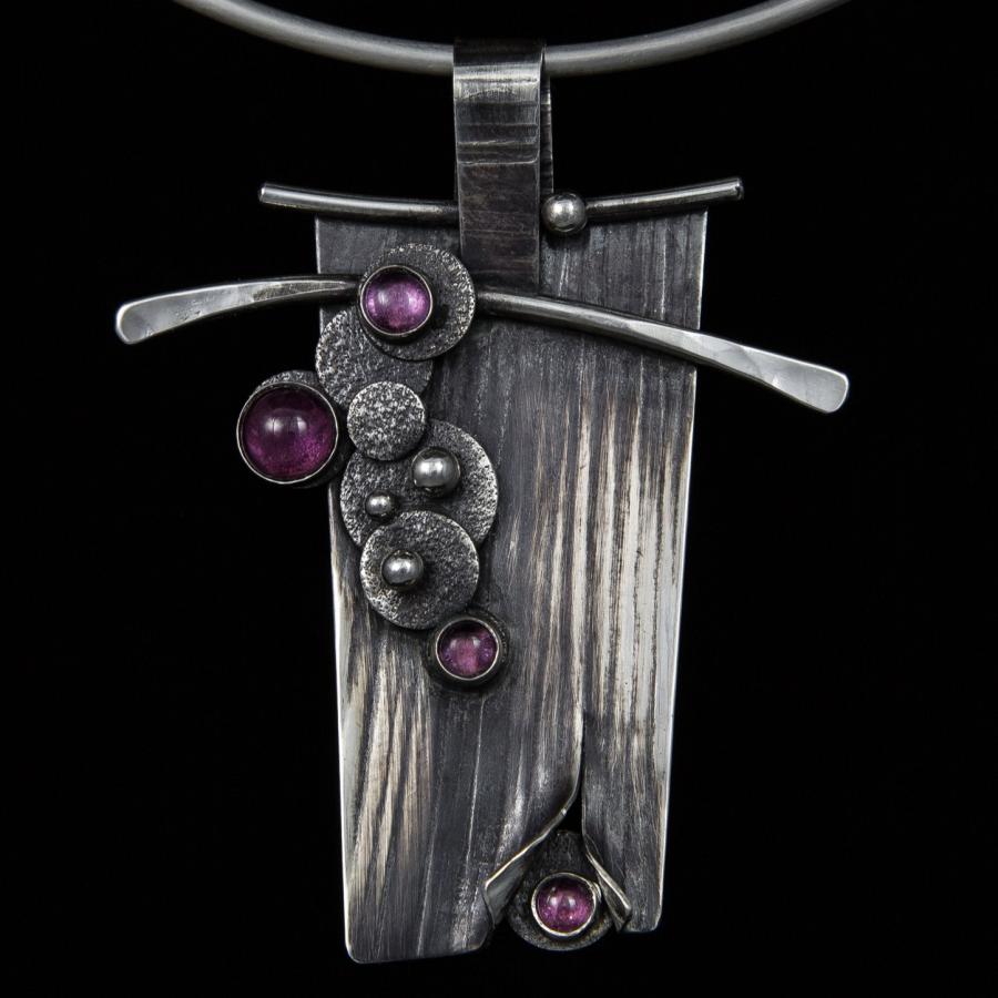Photograph of an artistic silver pendant necklace.