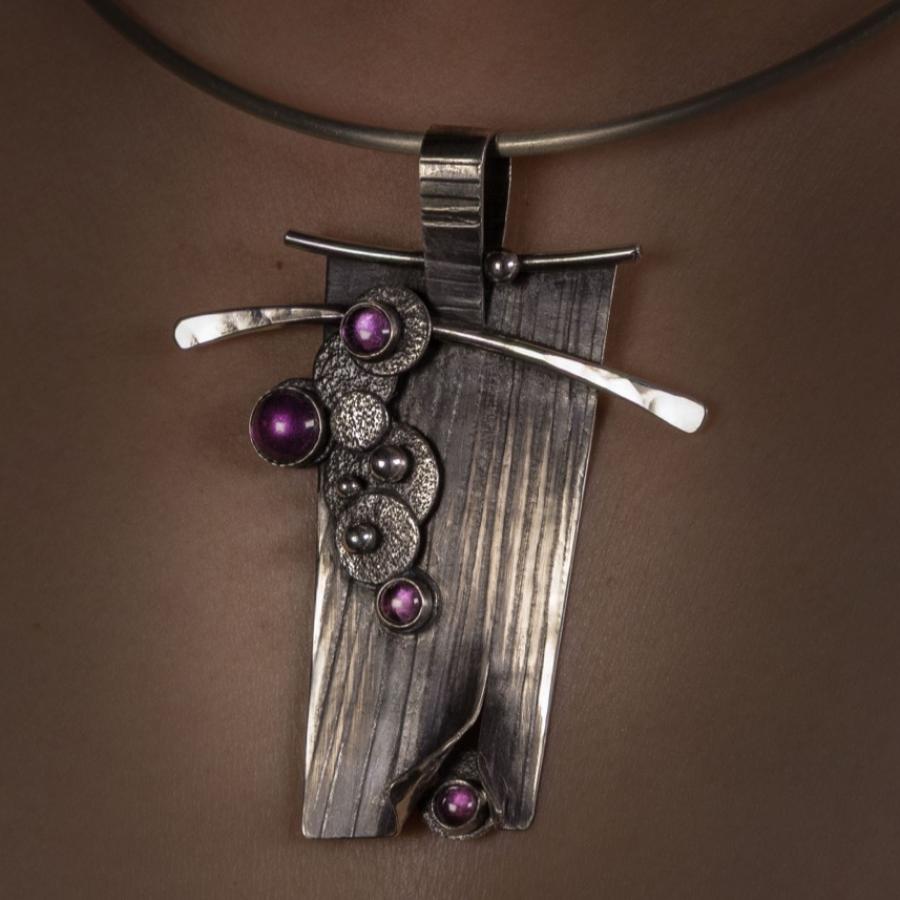 Close-up of silver necklace with purple gems.