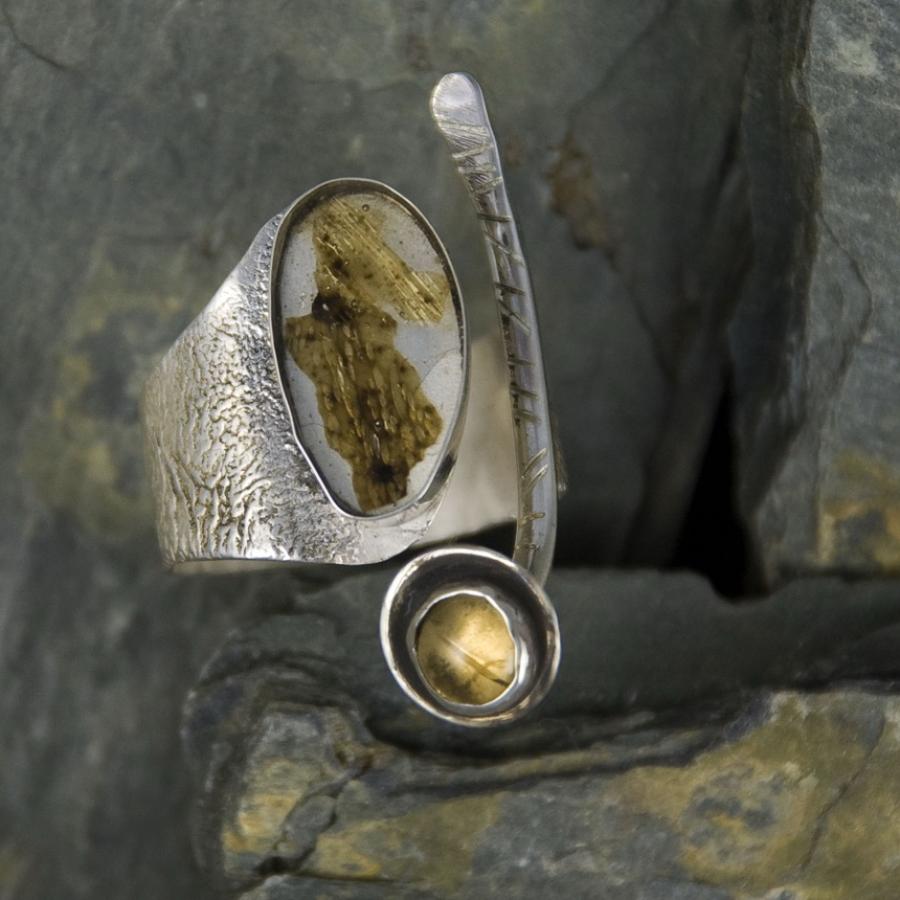 Silver ring with gold accents on a dark stone background.