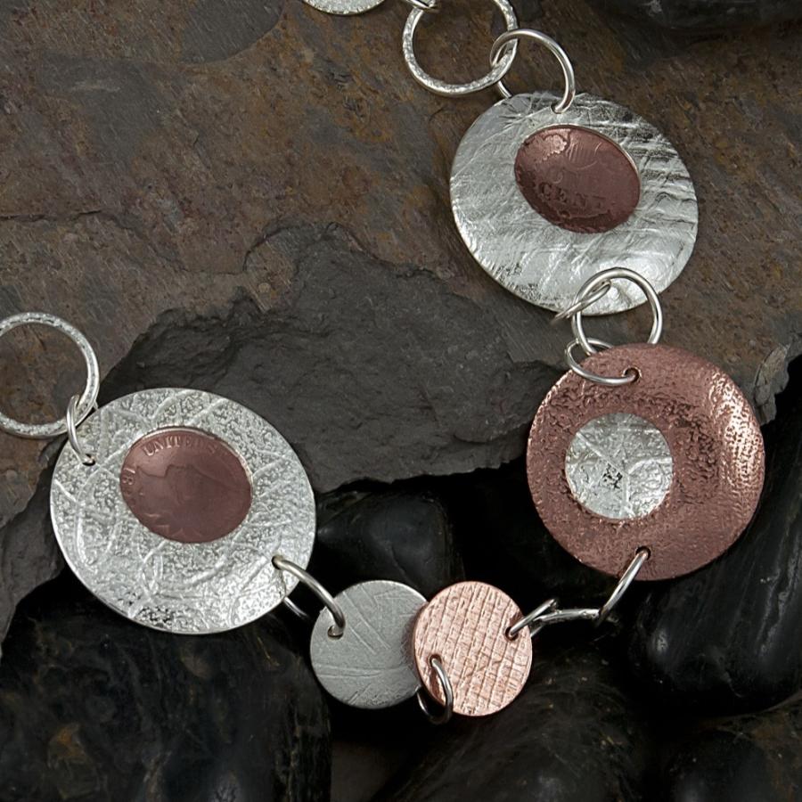 Silver and copper disc necklace on slate.