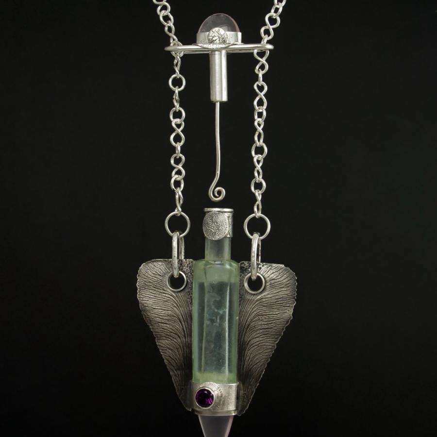 Silver necklace with glass vial pendant.