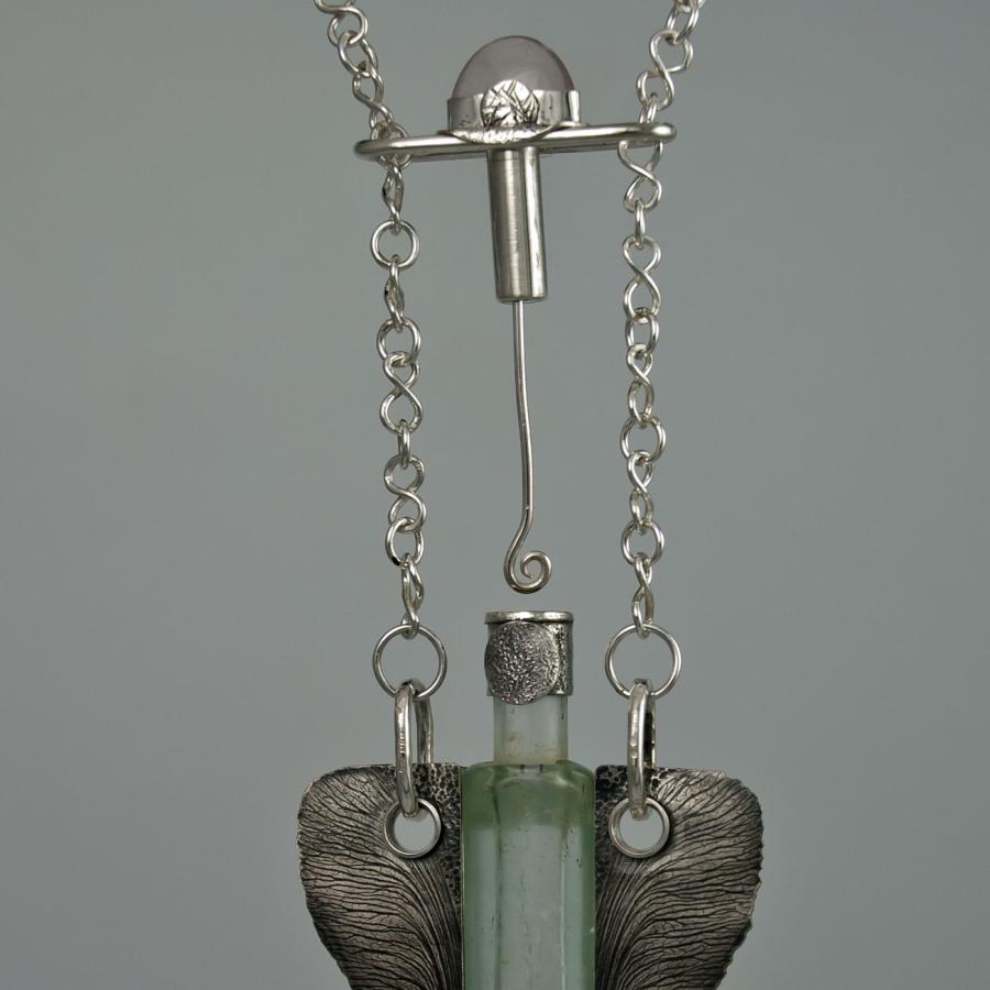 Silver necklace with glass vial pendant.