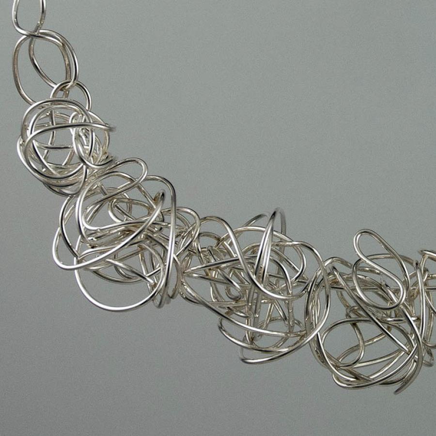 Silver wire necklace with tangled knot design, close-up photograph.