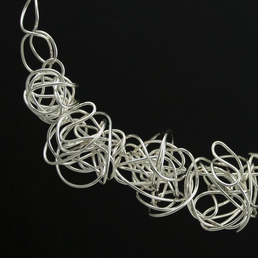 Silver wire necklace against a black background.