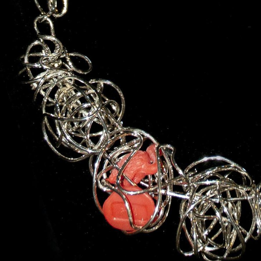 Necklace with silver wire and plastic toy, close-up.