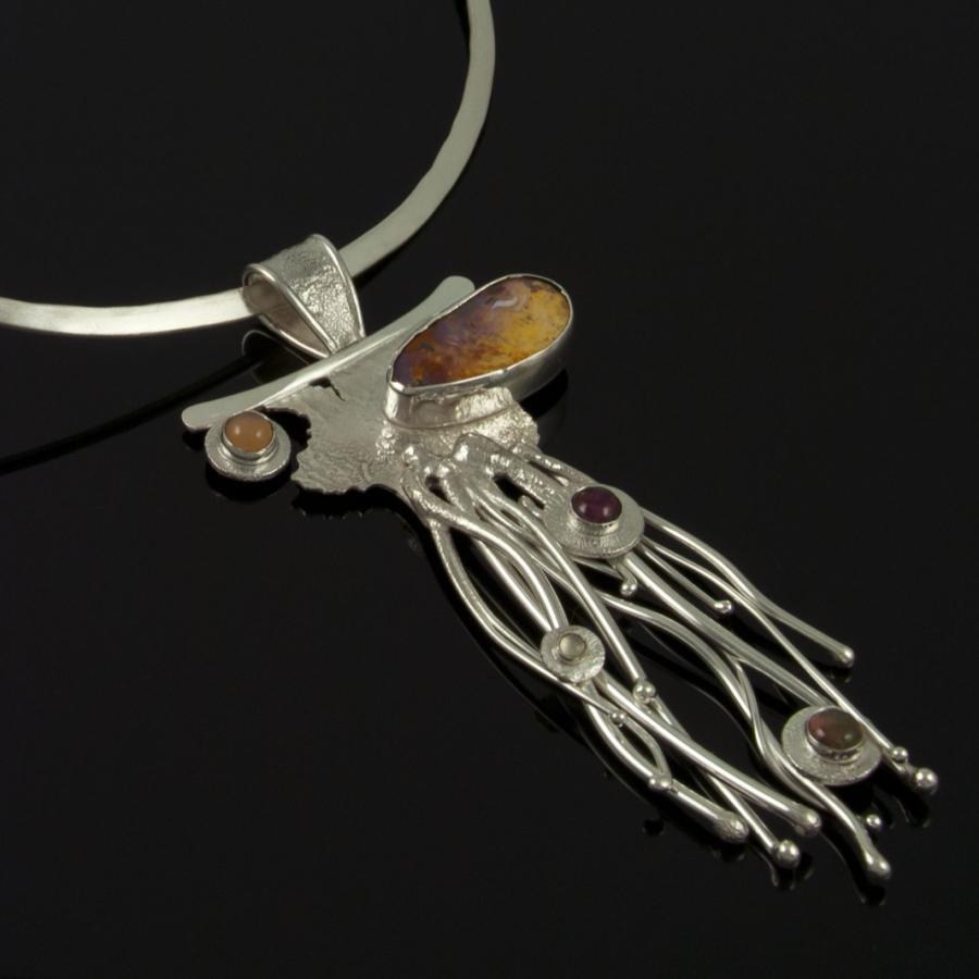 Silver pendant necklace on a black background.