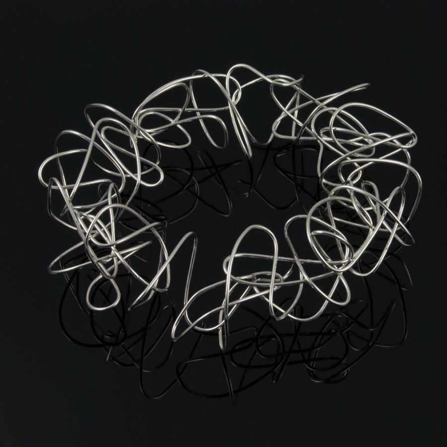 Silver wire bangle on black background.