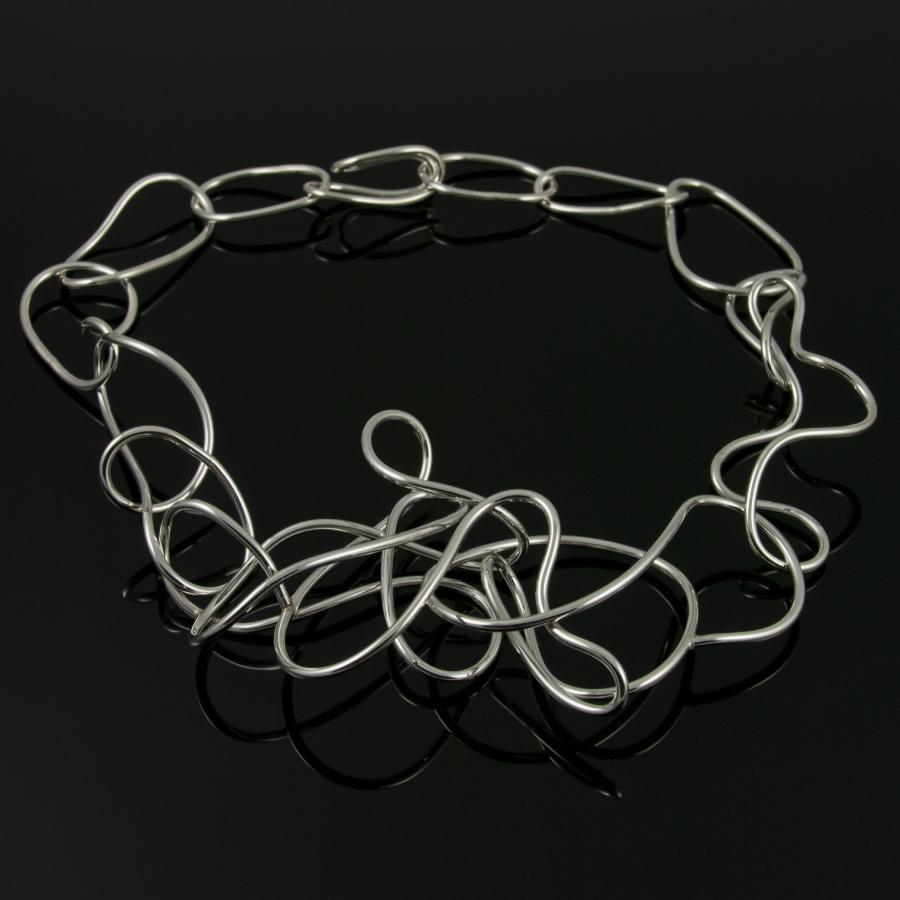 Silver chain link necklace on black surface.
