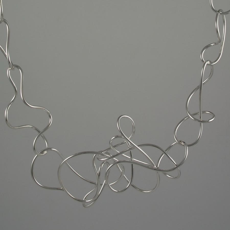 Wire art in necklace shape on grey background.