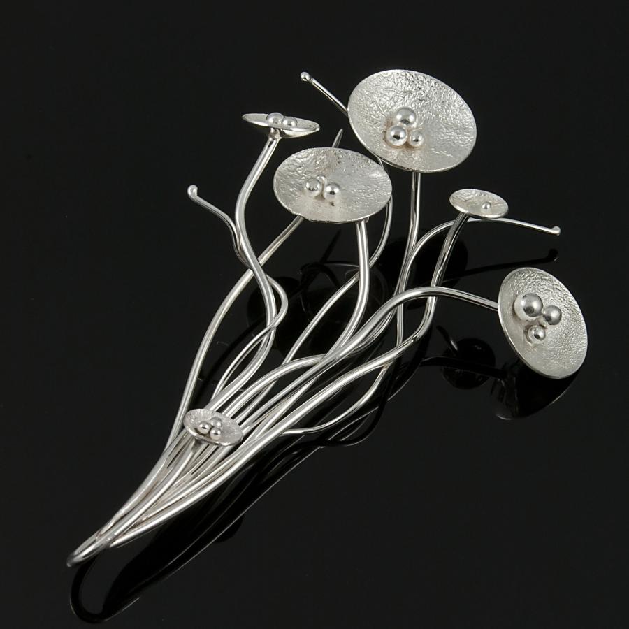 Silver flower brooch on a black background.