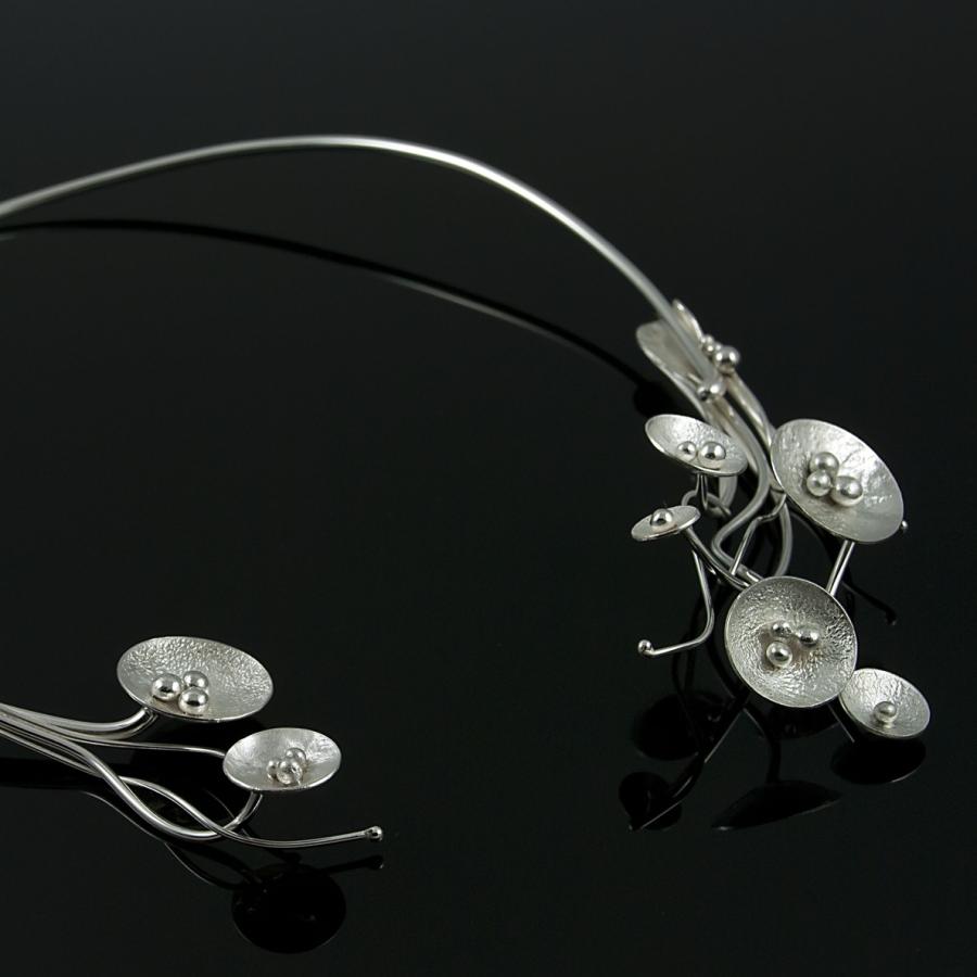 Silver wire collar necklace with circular and seed pod-like accents.