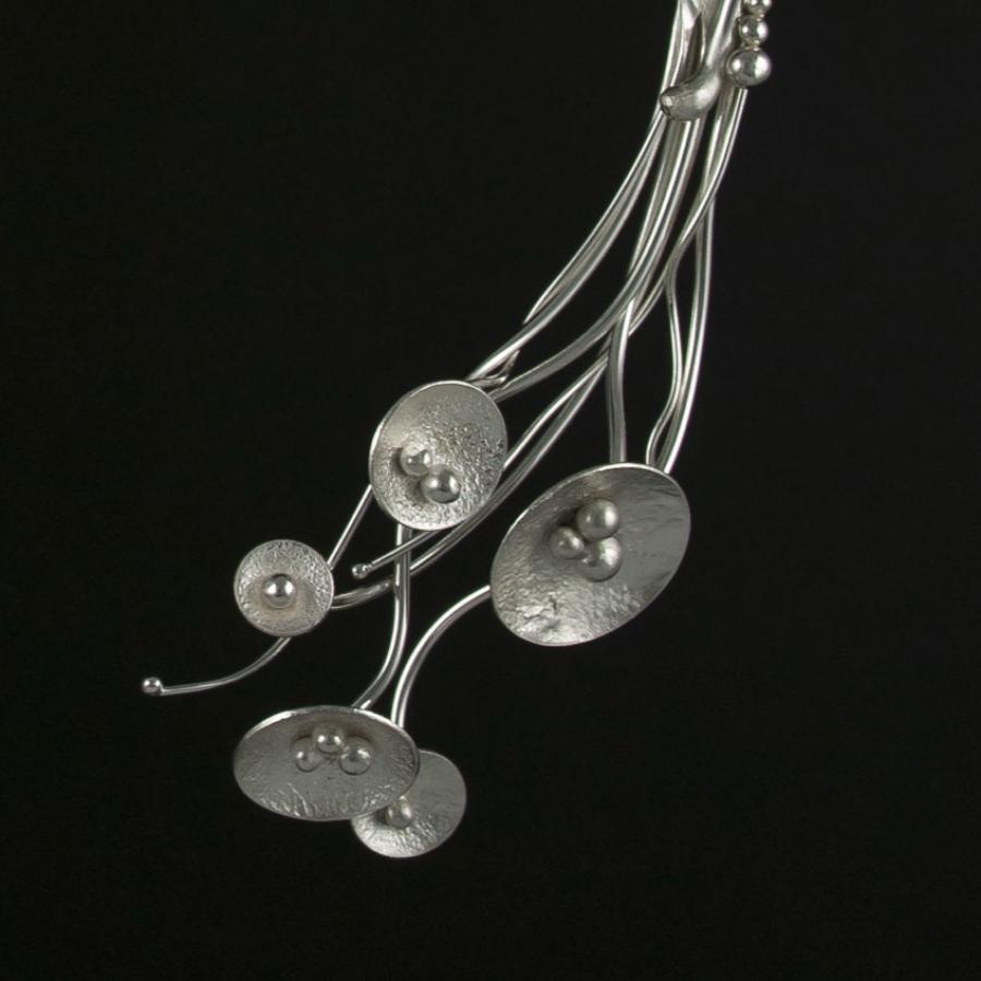 Silver wire collar necklace with circular and seed pod-like accents.