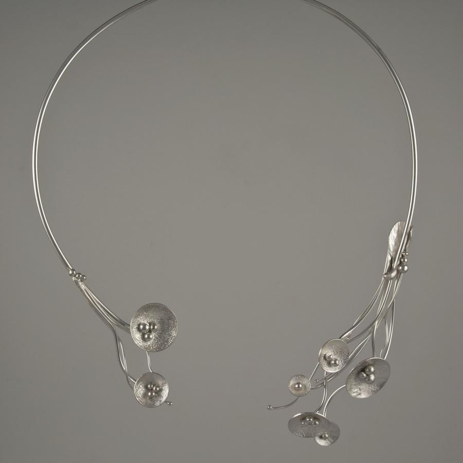 Silver wire collar necklace with circular and seed pod-like accents.