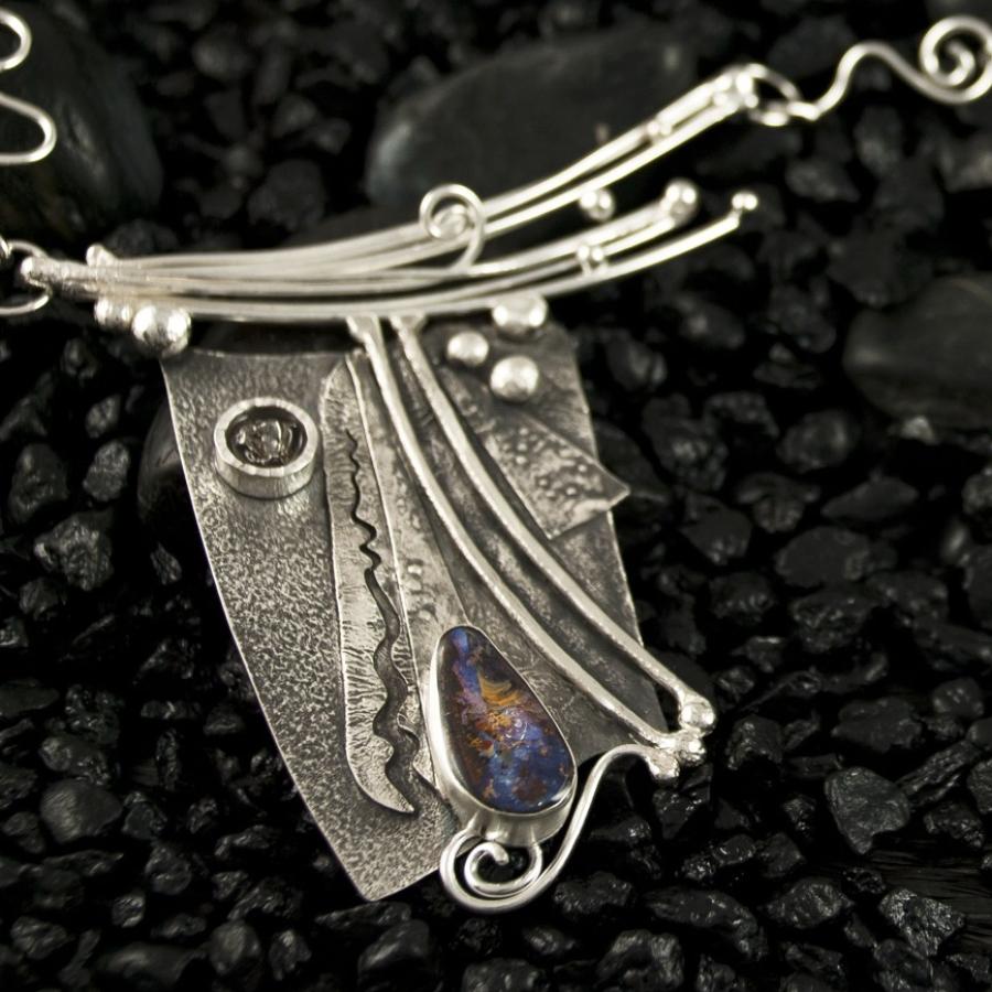 Handmade silver pendant necklace on black stones.
